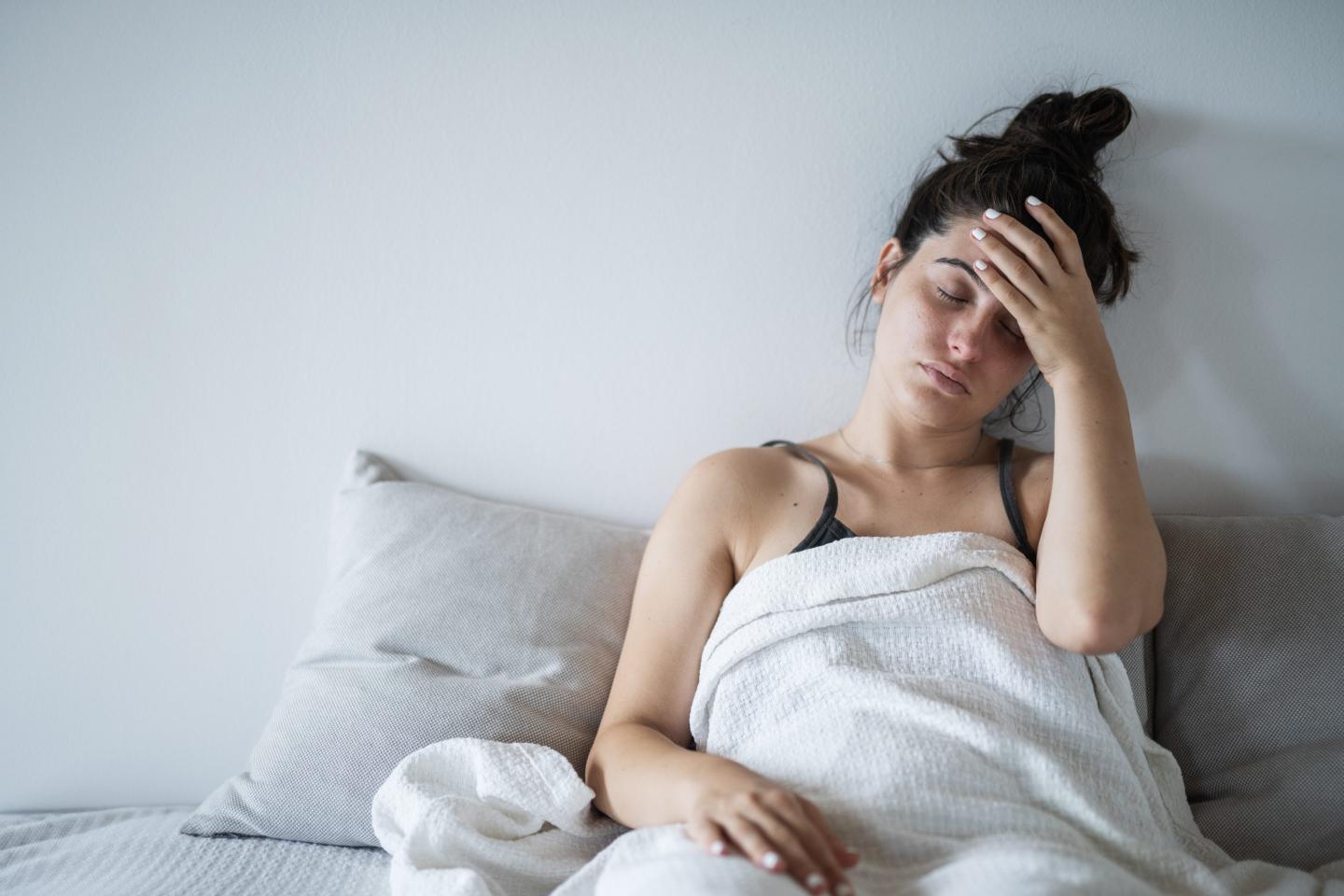 Young woman having a fever. She is holding her head because of a headache.