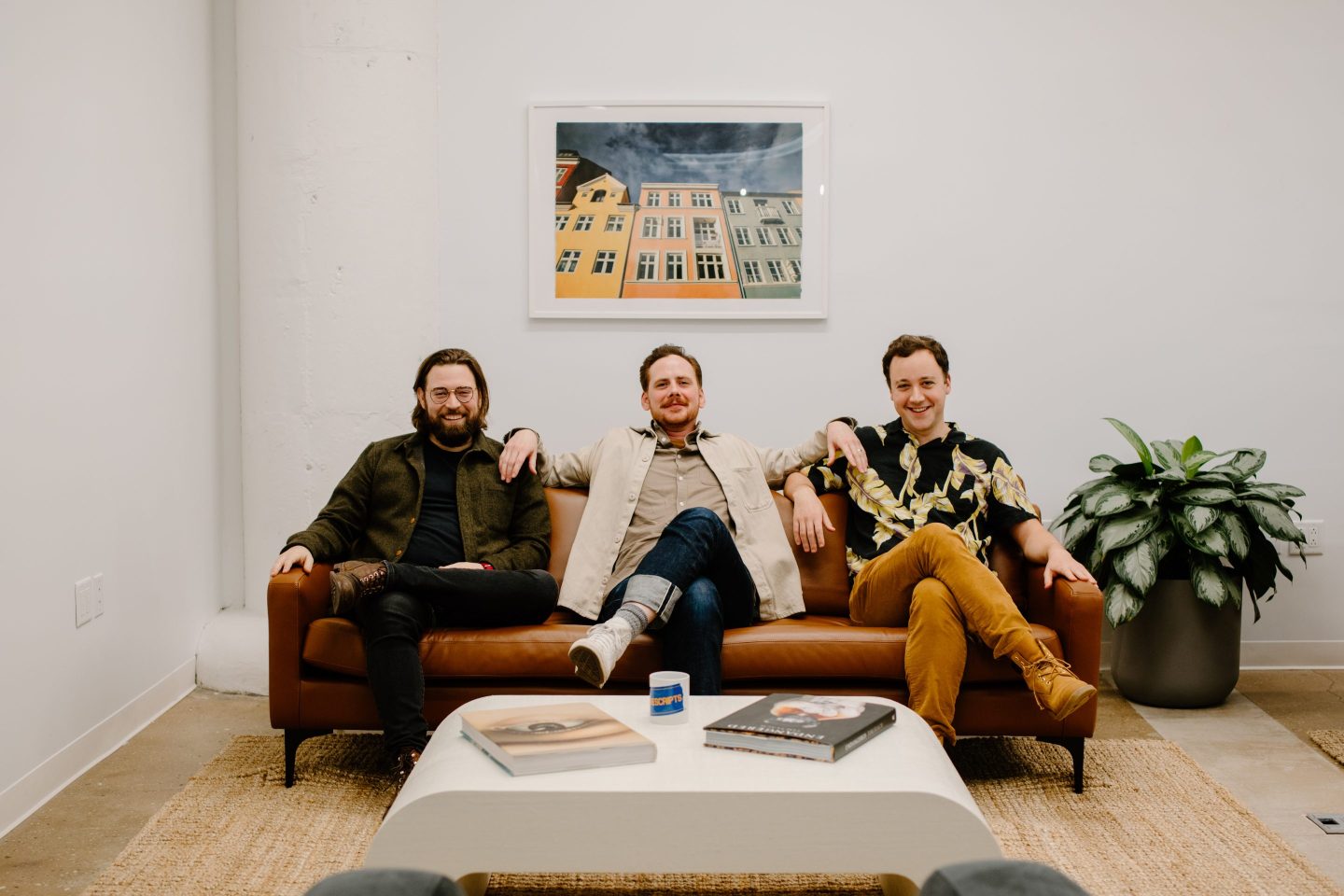 The three founders of Photon Health sitting on a brown sofa and posing for a photo.