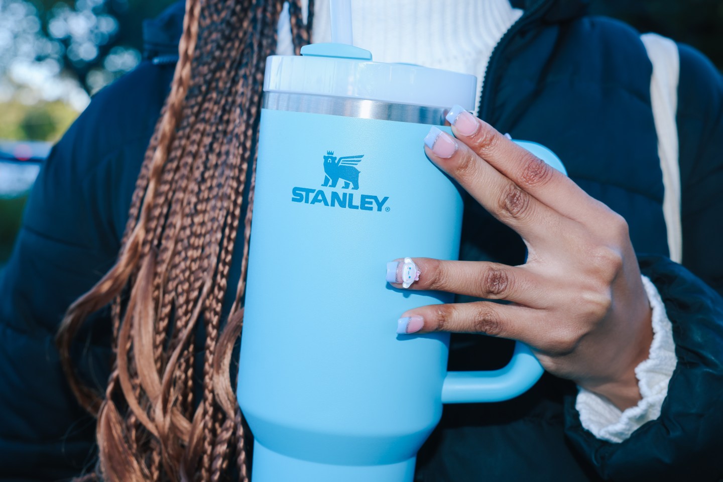 A high school student holds a light blue Stanley water bottle
