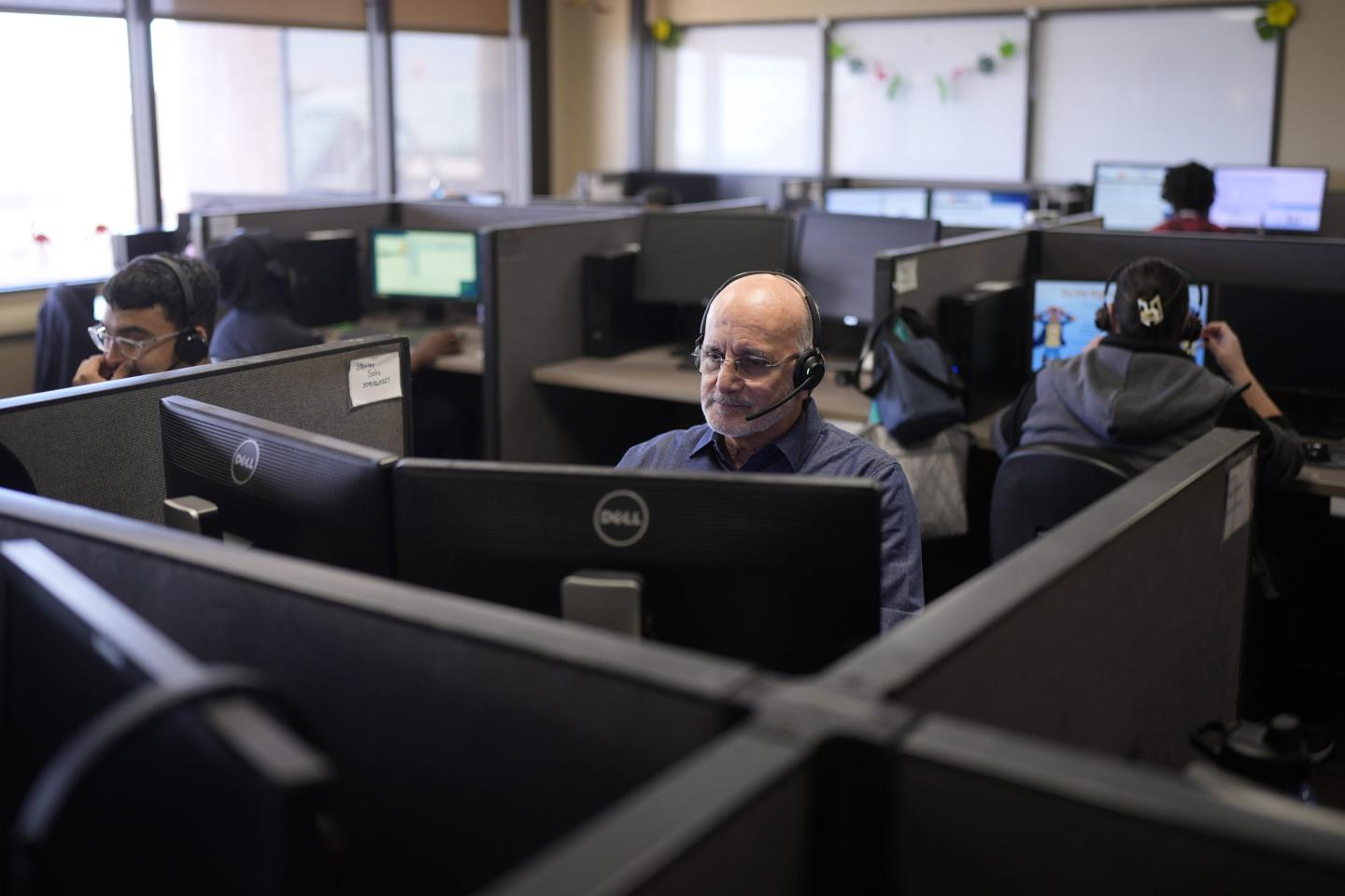 Customer Experience Representatives Stanley Solis, center, and other representatives take calls at an Alorica center, on Aug. 19, 2024, in San Antonio.