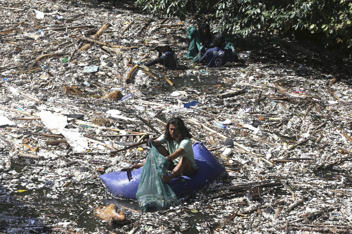 A woman sifts through a mountain of plastic waste