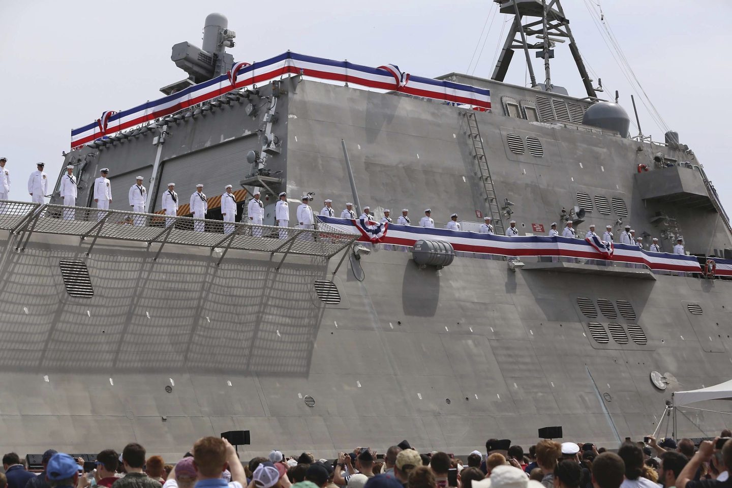 Thousands attend the commissioning ceremony for the USS Manchester at the New Hampshire State Pier in Portsmouth, N.H. Officers are seen on the side of the boat standing, facing the crowd.