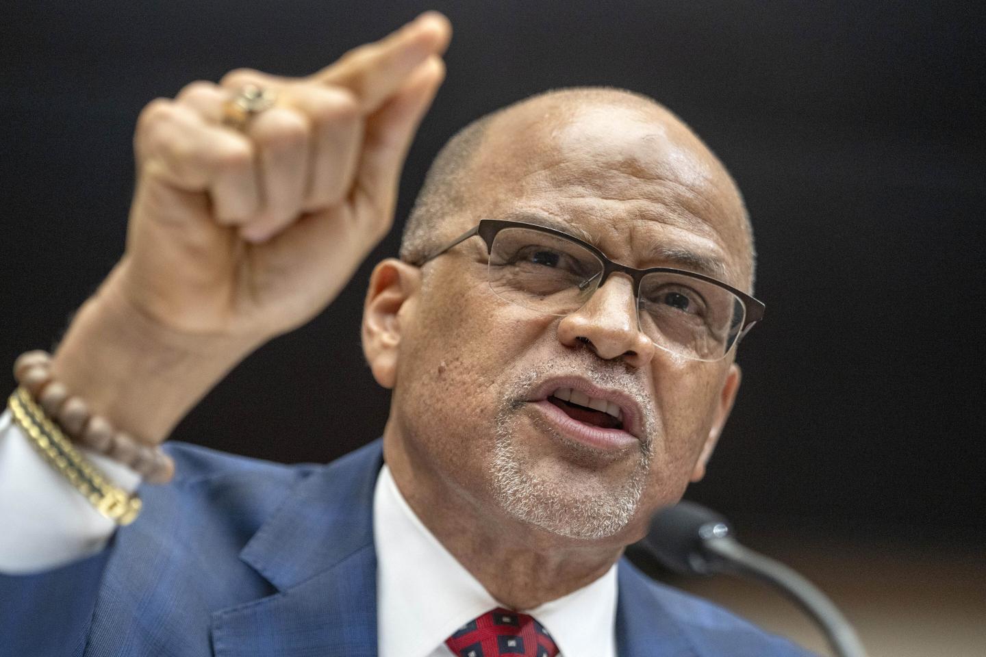 David Banks, chancellor of New York Public schools, is seen at a hearing answering questions in front of a microphone. His mouth is open as he speaks and he is gesturing with his right hand.