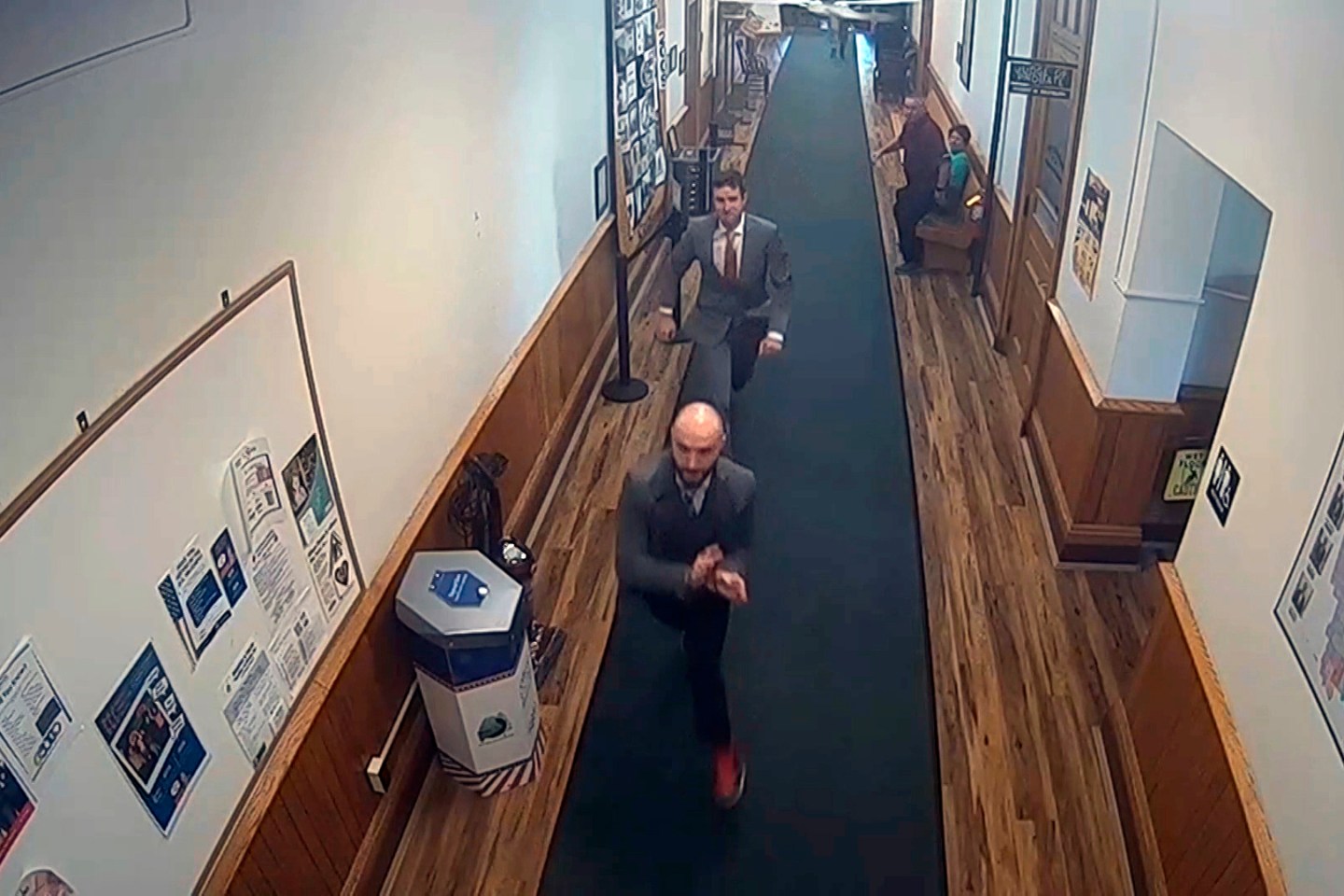 In this image taken from video provided by TMX, Nicholas Carter, 31, attempts to flee the Somerset County Courthouse in handcuffs. You can see the courtroom hallway and chase scene in a fisheye lens perspective.