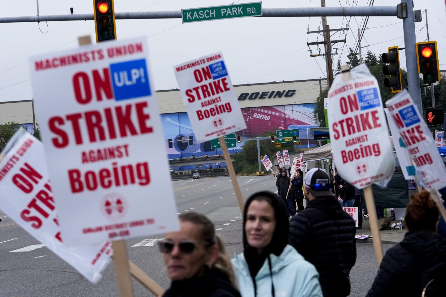 Boeing workers wave picket signs as they strike after union members voted to reject a contract offer, on Sept. 15, 2024, near the company's factory in Everett, Wash.