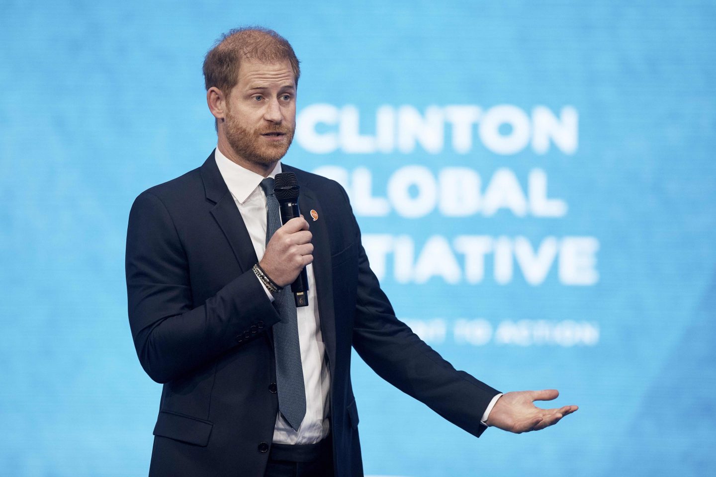 Prince Harry speaks during the Clinton Global Initiative. He is in a suit and holding a mic.