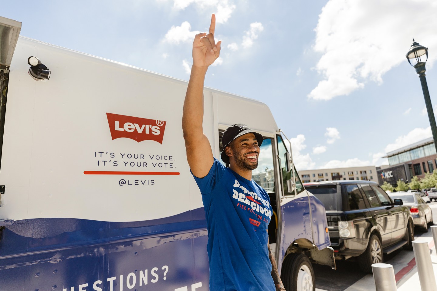 Man celebrating with arm up in front of a truck with Levi's logo as part of their voter registration initiative.