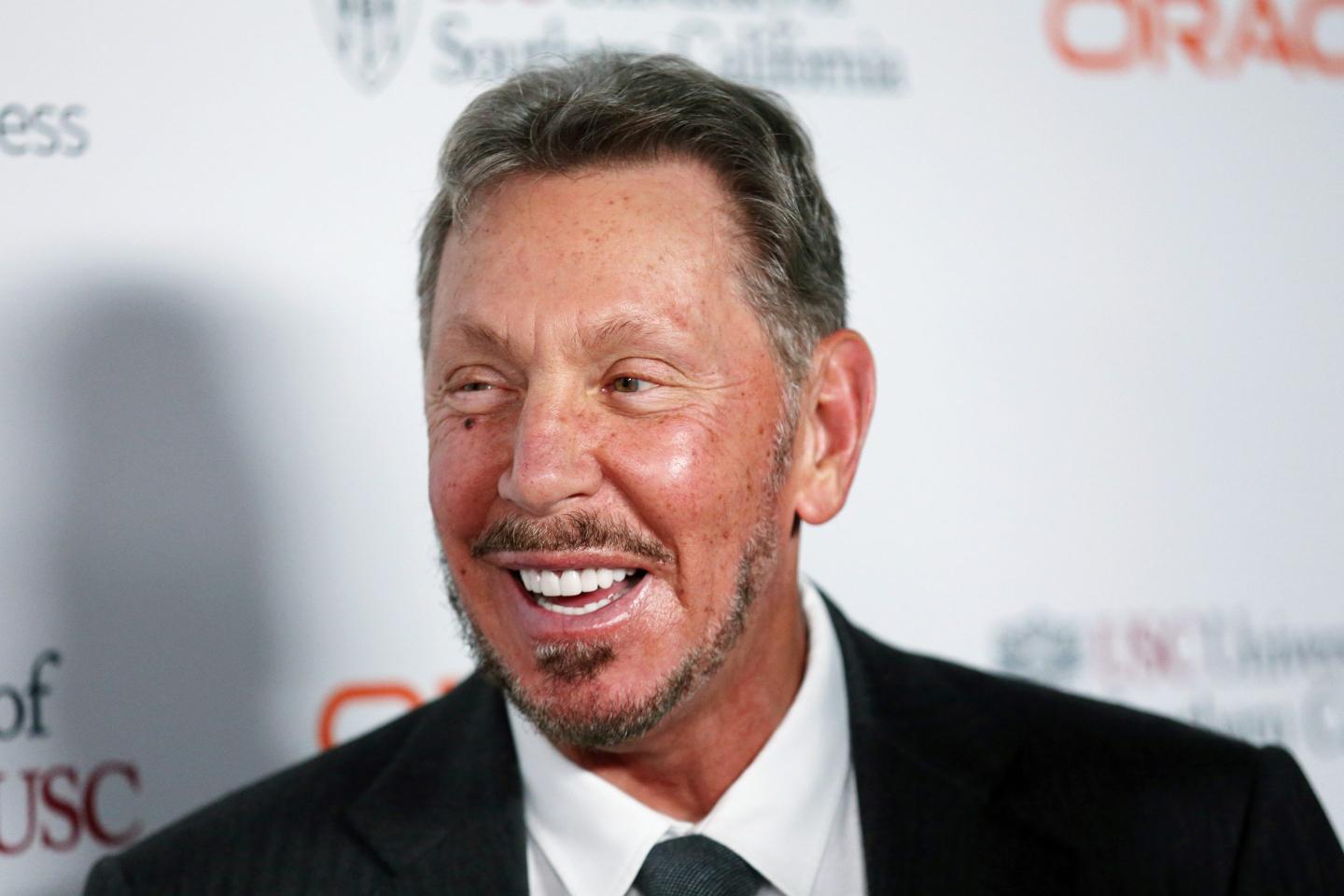 Larry Ellison, dressed in a suit, smiles and looks to his right.