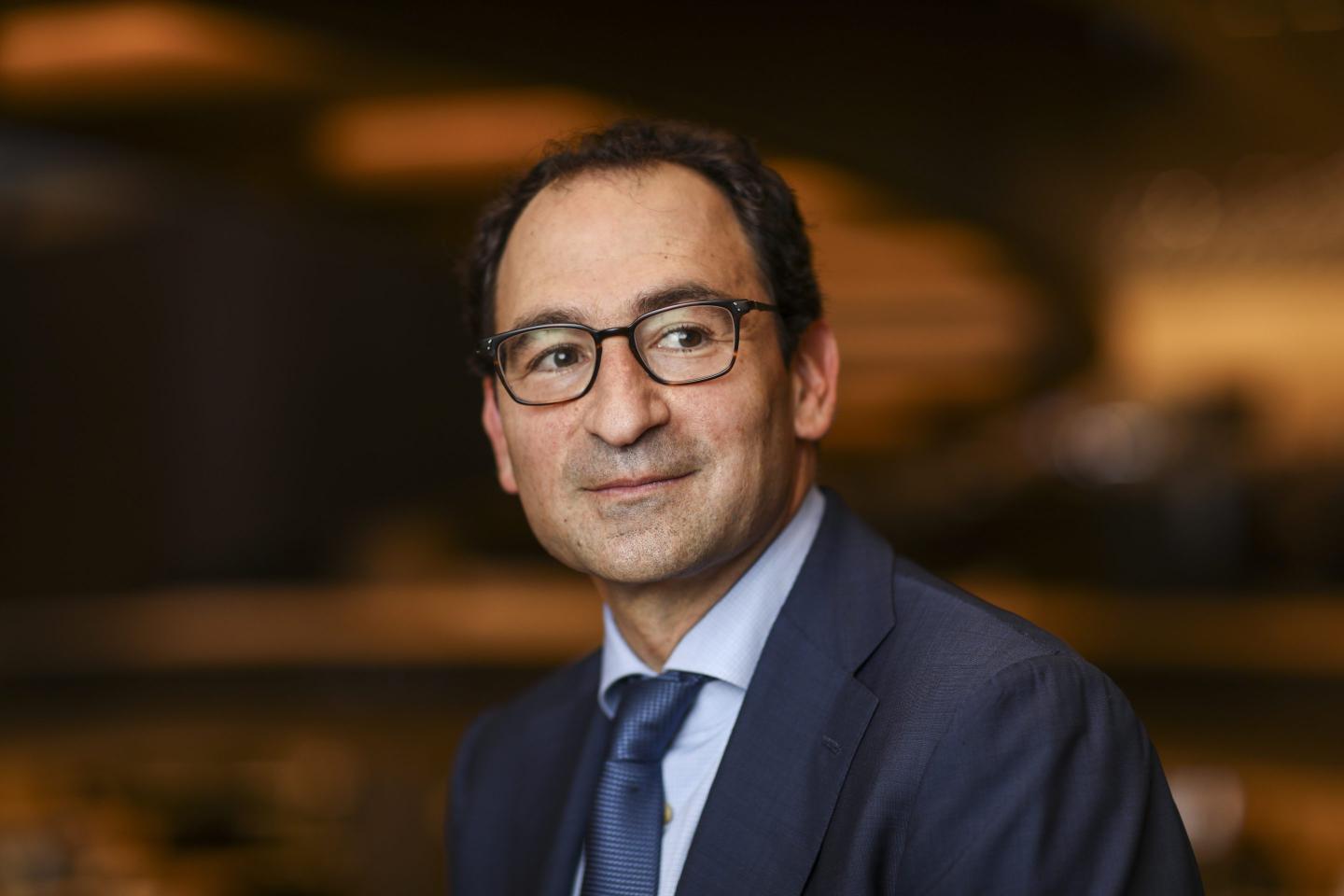 Jonathan Gray in a suit, wearing glasses and slightly smiling.