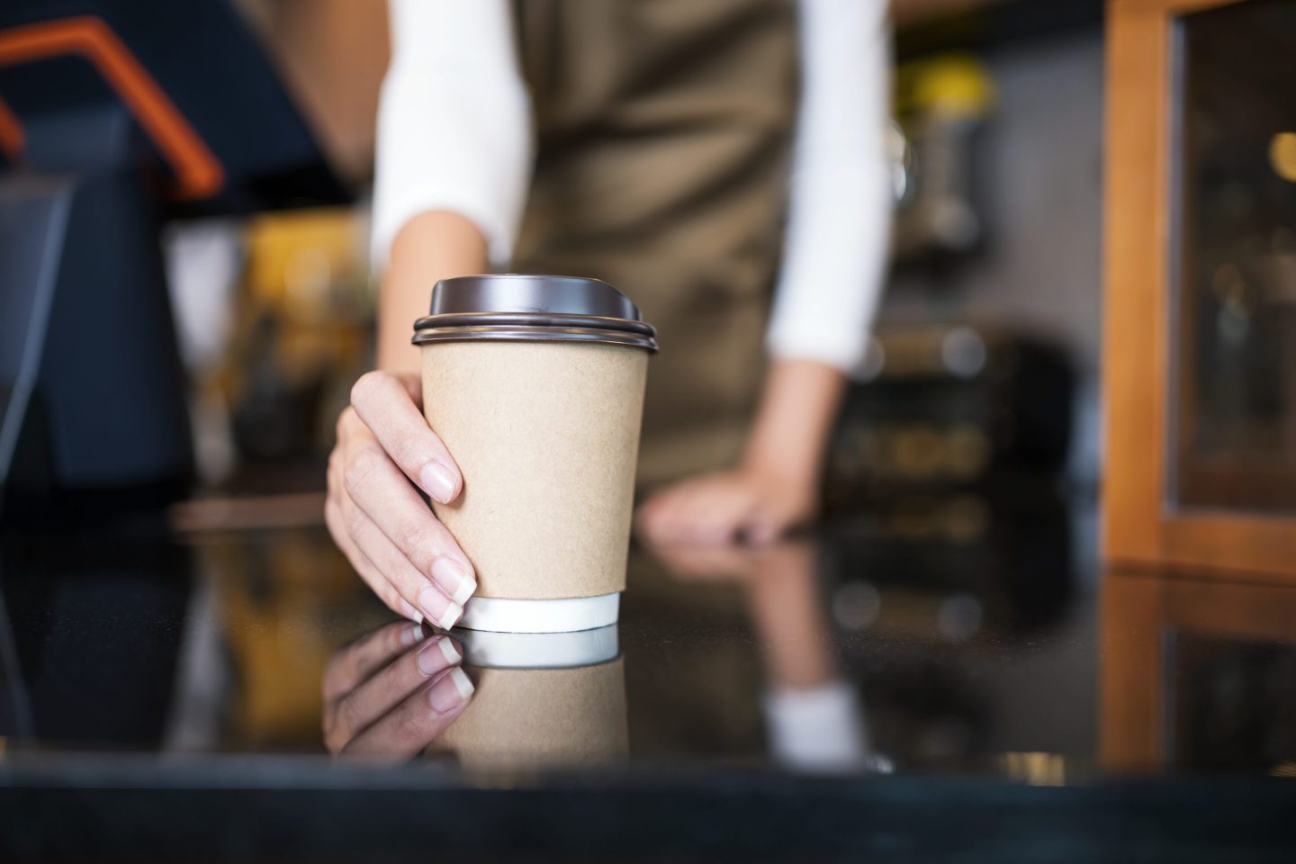 The unrecognizable waitress serving coffee to a customer in a cafe. Serving food and Drink.