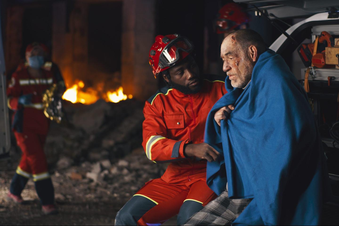 Paramedic helps elderly man amid fire.