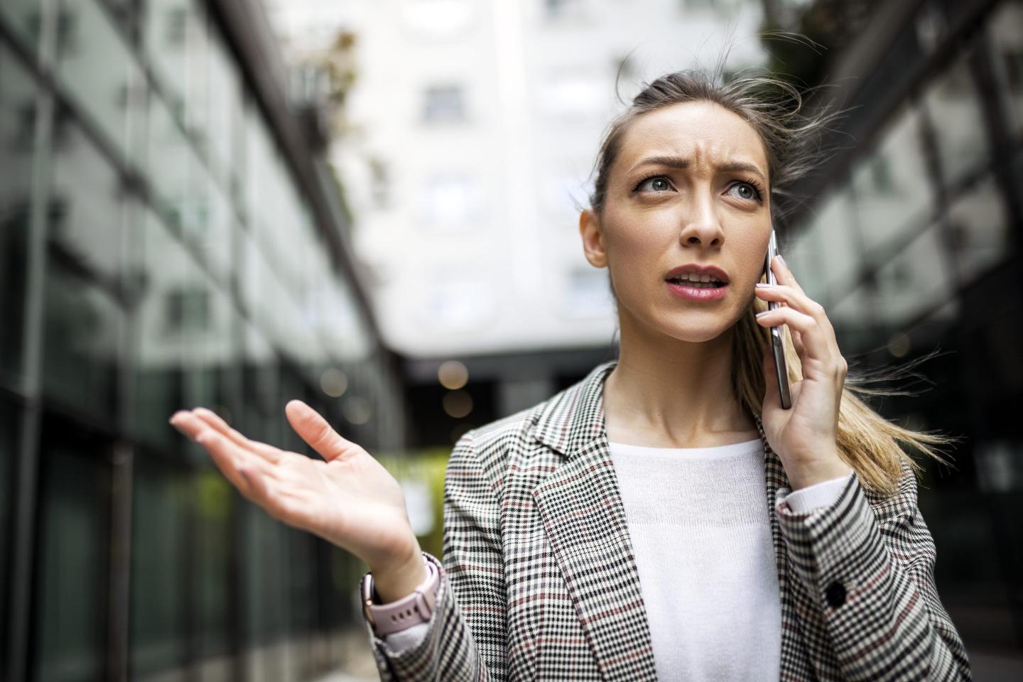 Angry-looking woman using her cell phone while walking