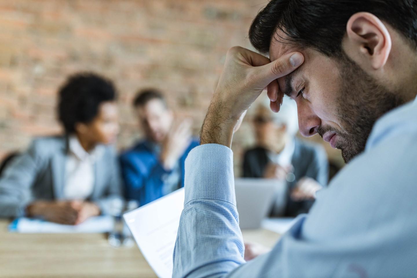 Young male candidate feeling worried while waiting for human resource team to make a decision about his job on an interview in the office.