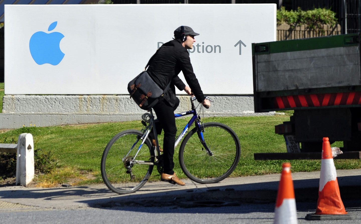 A cyclist rides a bicycle past a sign at Apple Inc.'s campus in Cork, Ireland.