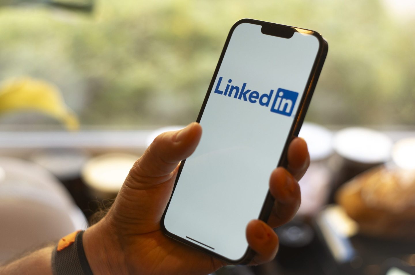 A person holds a mobile phone with the Linkedin app open on screen