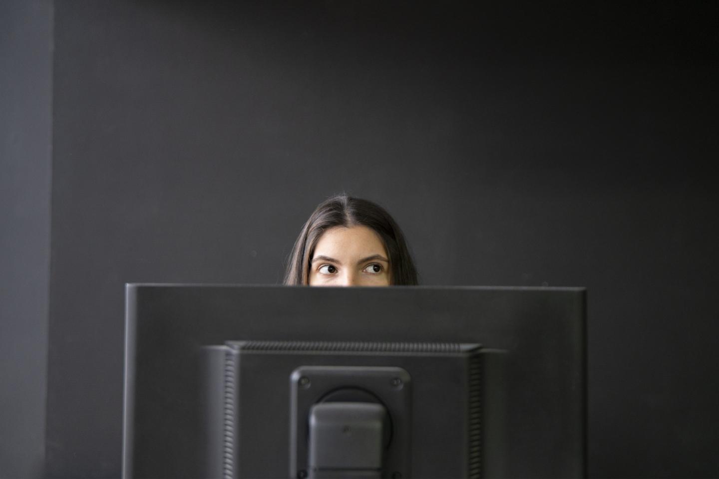 Office worker being sneaky behind computer.