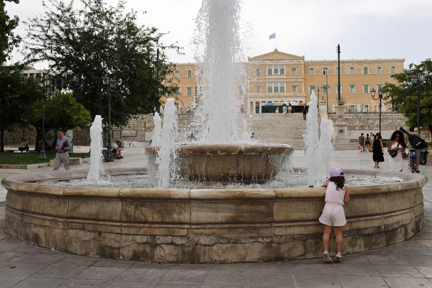 A girl plays in a fountain at Syntagma square