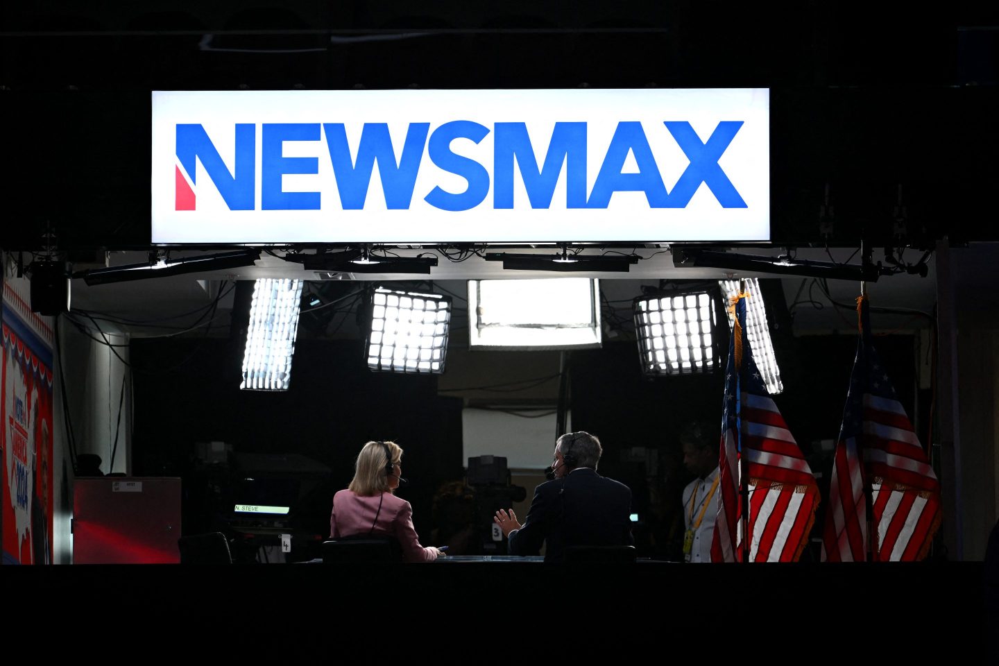 News anchors work at Newsmax's booth