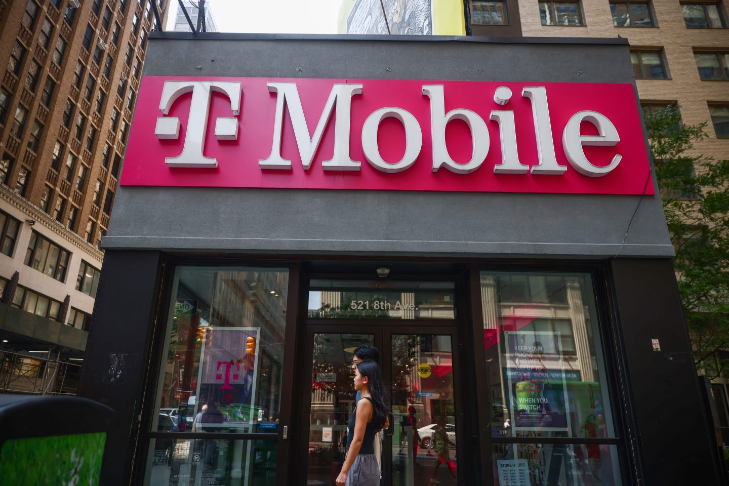 The exterior of a New York T-Mobile store shows passersby near the entrance.