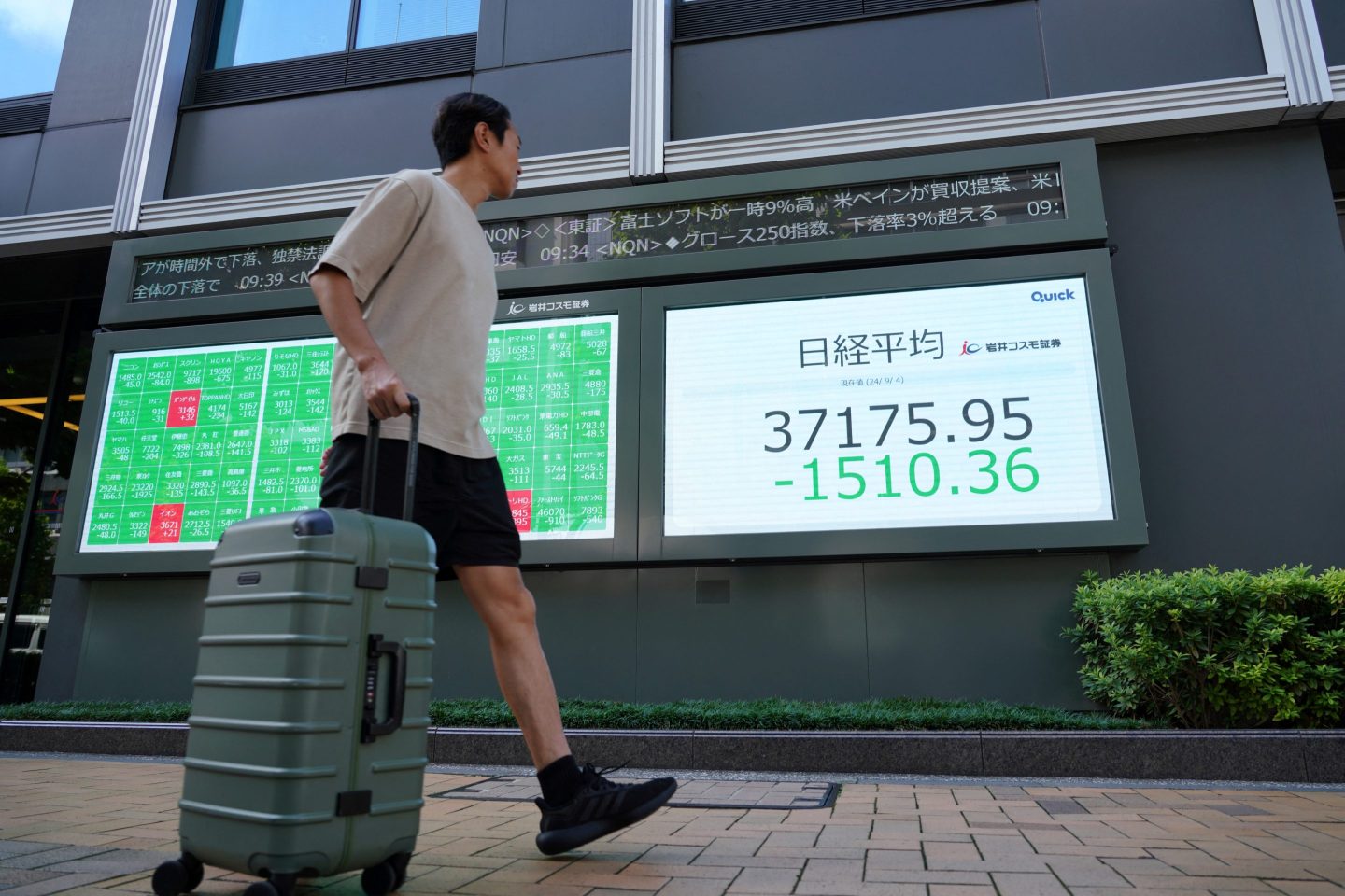 A man walks in front of an electronic quotation board displaying share prices on the Tokyo Stock Exchange