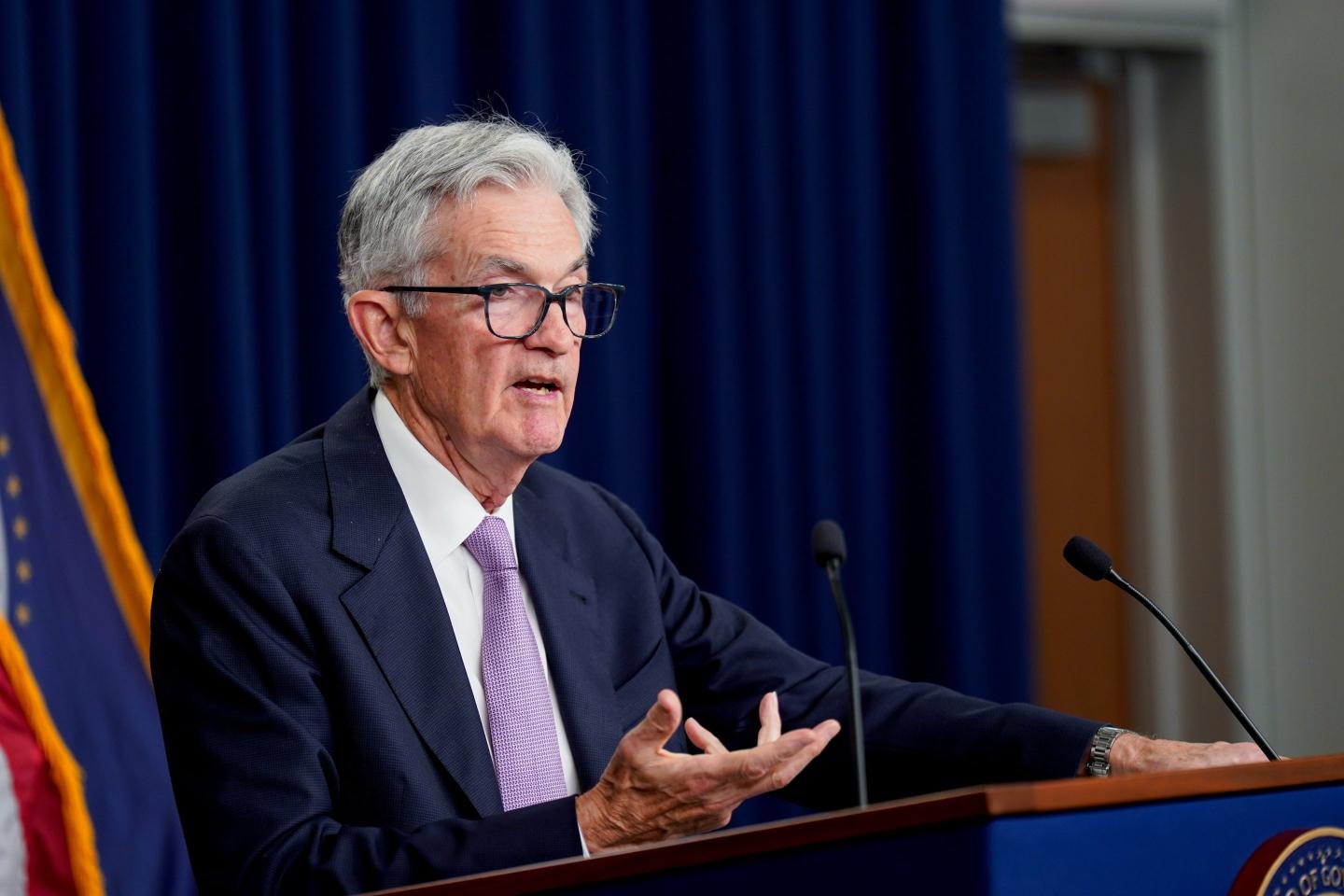 Fed chair Jerome Powell motions with his right hand as he speaks at a podium.