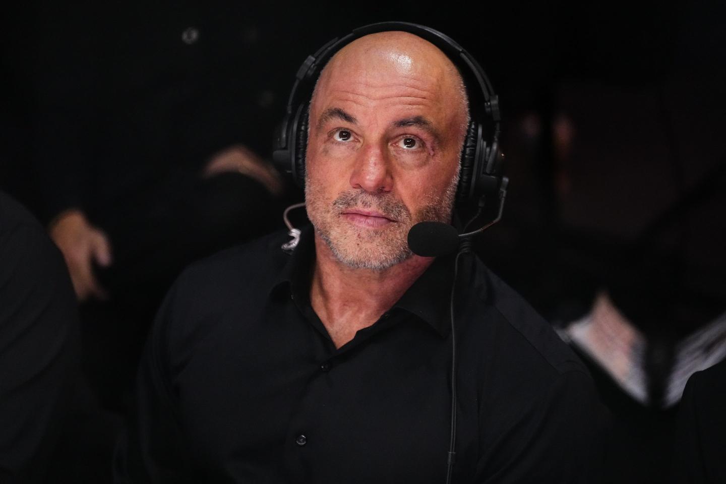 oe Rogan looks on during the UFC 306, he is wearing black and a black headset with microphone.