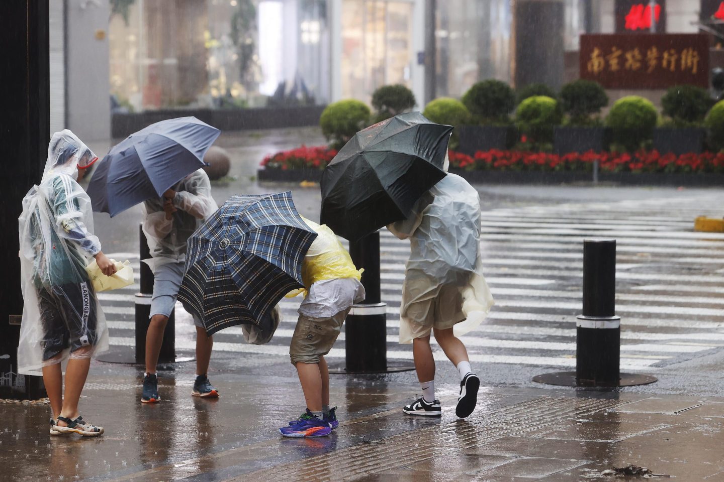 Pedestrians struggle with their umbrellas in strong winds and rain brought by typhoon Bebinca on the Nanjing East Road pedestrian street on Sept. 16, 2024 in Shanghai.