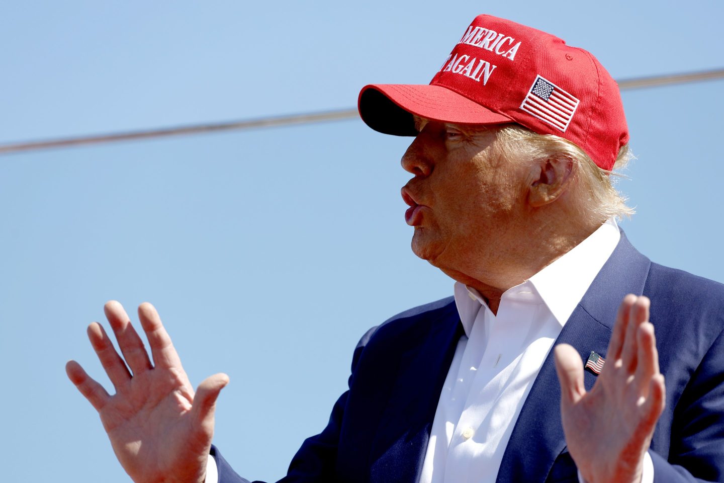 Trump is seen at a rally wearing a Make America Great Again red cap.