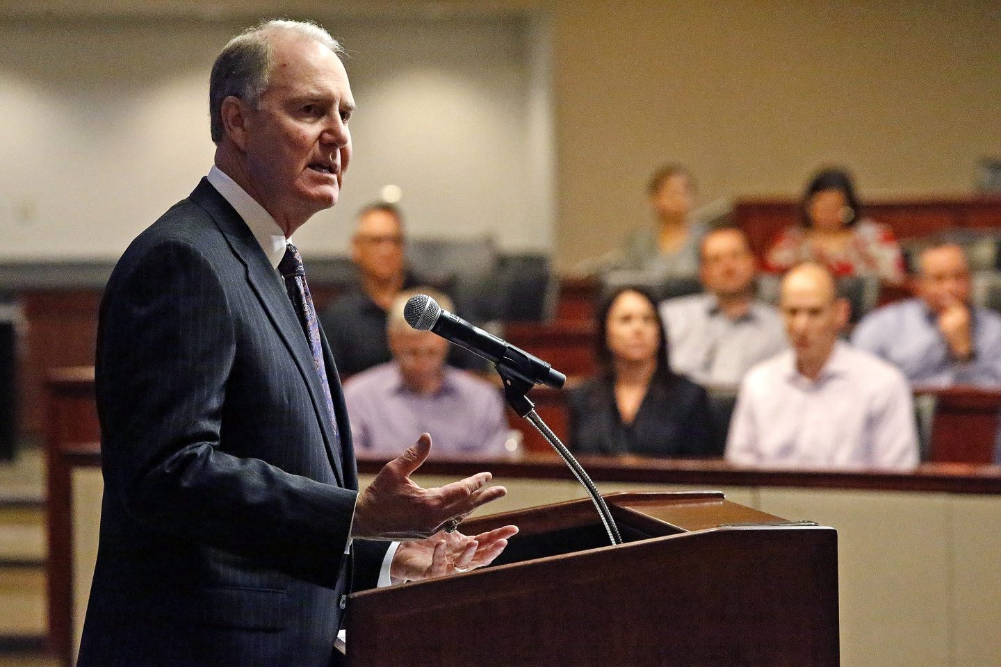 Southwest chairman Gary Kelly grimaces and lifts both hands, palms up, as he speaks at a podium during a press conference.