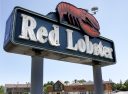 A large, outdoor Red Lobster sign is displayed with the brand's iconic red lobster logo. The sign features white, illuminated letters against a dark blue background.