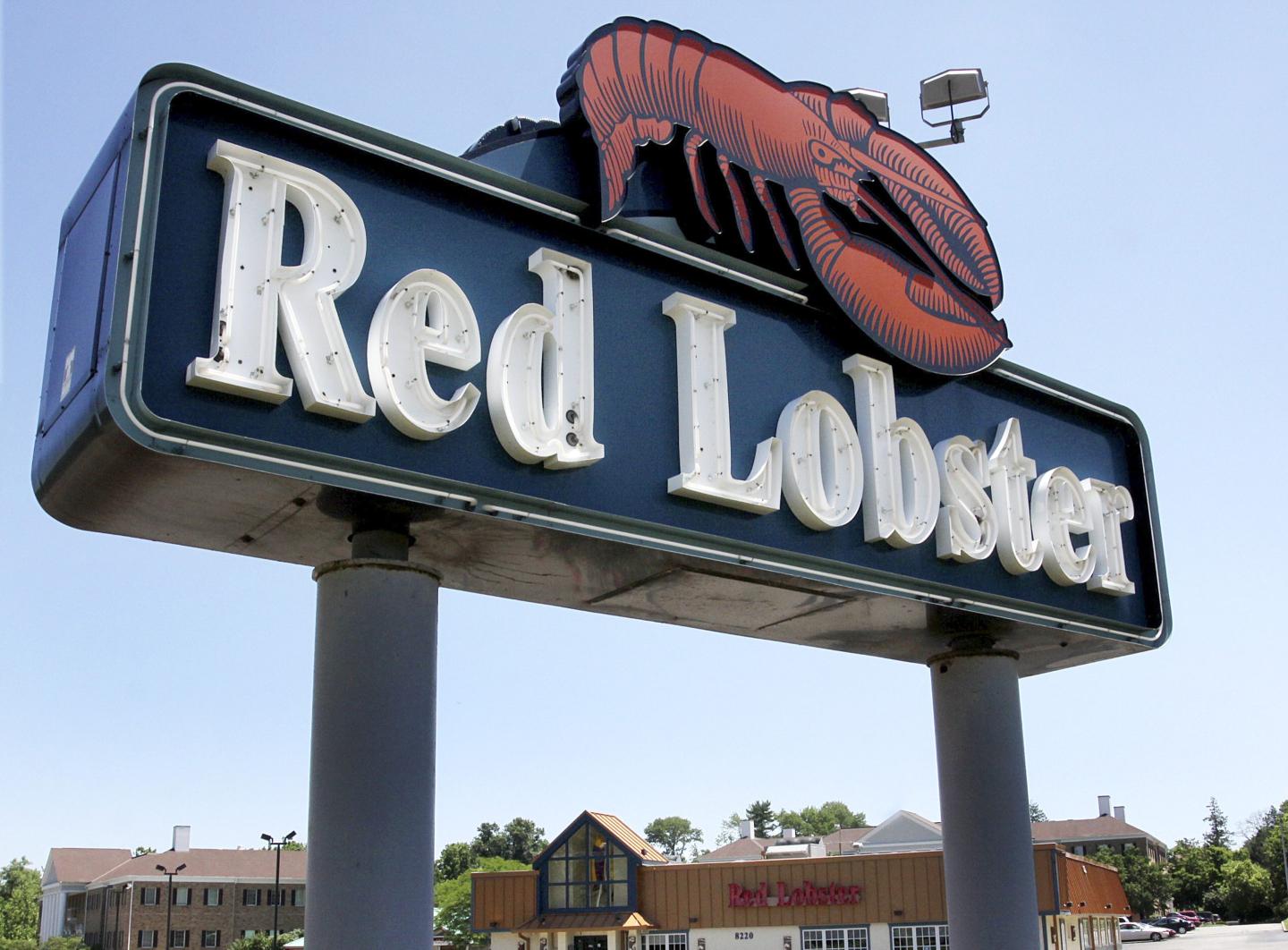 A large, outdoor Red Lobster sign is displayed with the brand's iconic red lobster logo. The sign features white, illuminated letters against a dark blue background.