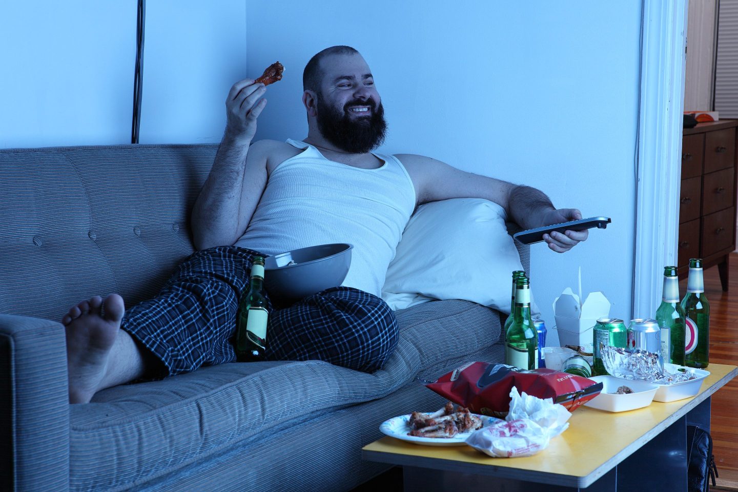 man on sofa watching TV and eating