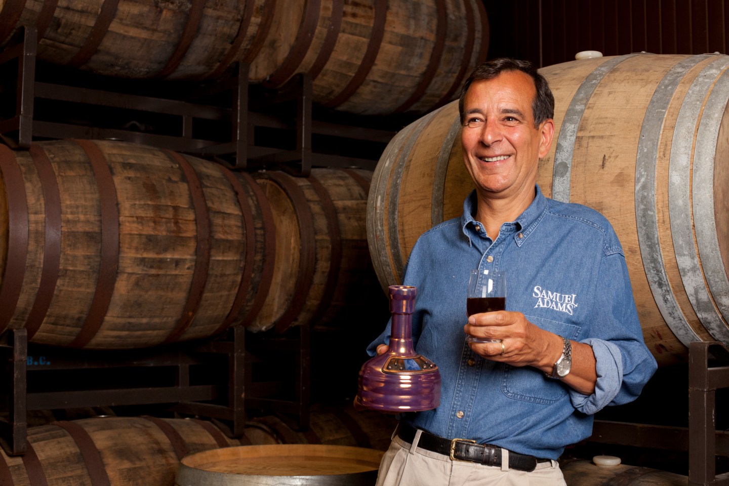 Founder and Brewer Jim Koch stands in front of barrels of beer.