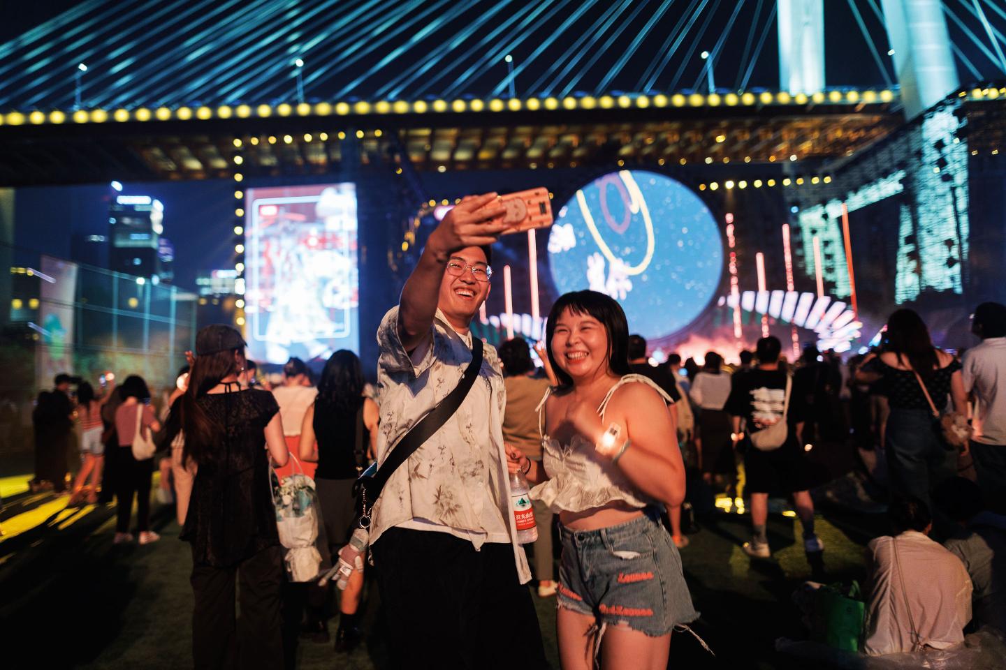 A couple in Honk Kong takes a selfie with a crowd behind them.