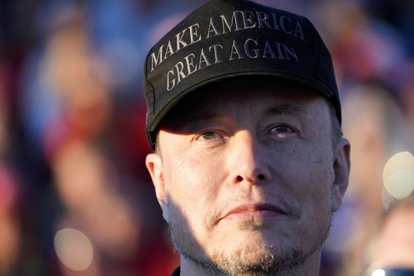 Elon Musk is seen wearing a black Make America Great Again hat.