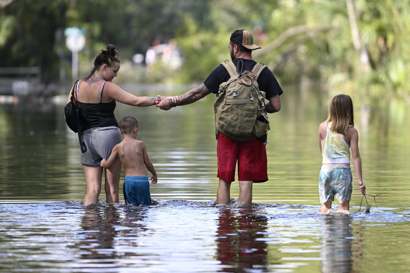 Dustin Holmes, second from right, holds hands with his girlfriend, Hailey Morgan, while returning to their flooded home with her children Aria Skye Hall, 7, right, and Kyle Ross, 4, in the aftermath of Hurricane Helene.