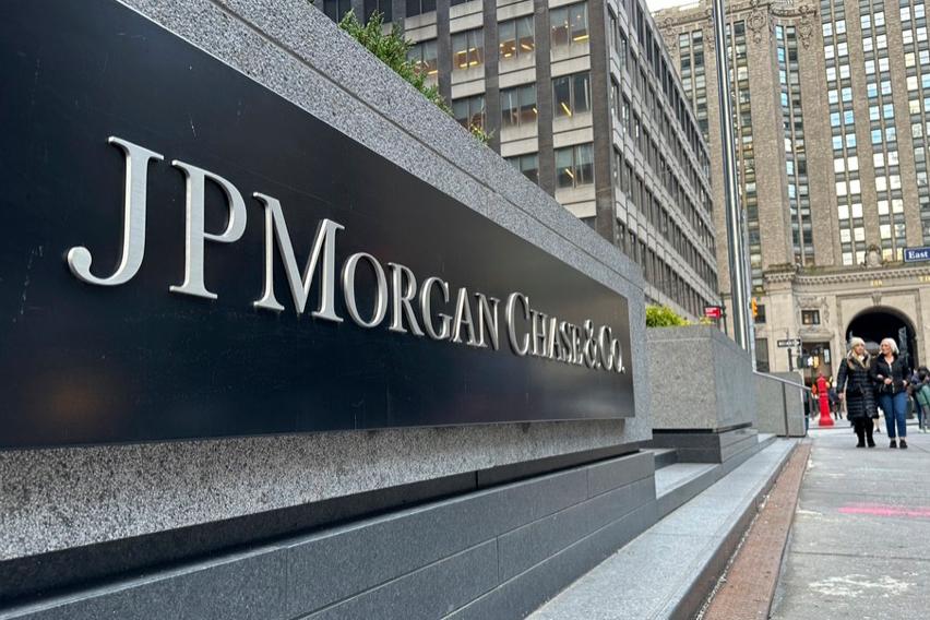 The JP Morgan headquarters sign is seen on the street with pedestrians in the background.