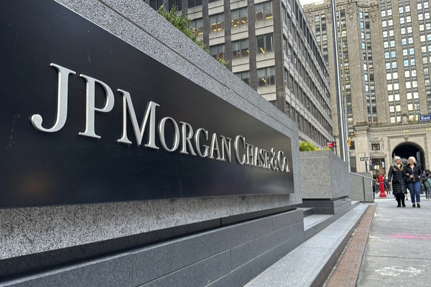 The JP Morgan headquarters sign is seen on the street with pedestrians in the background.
