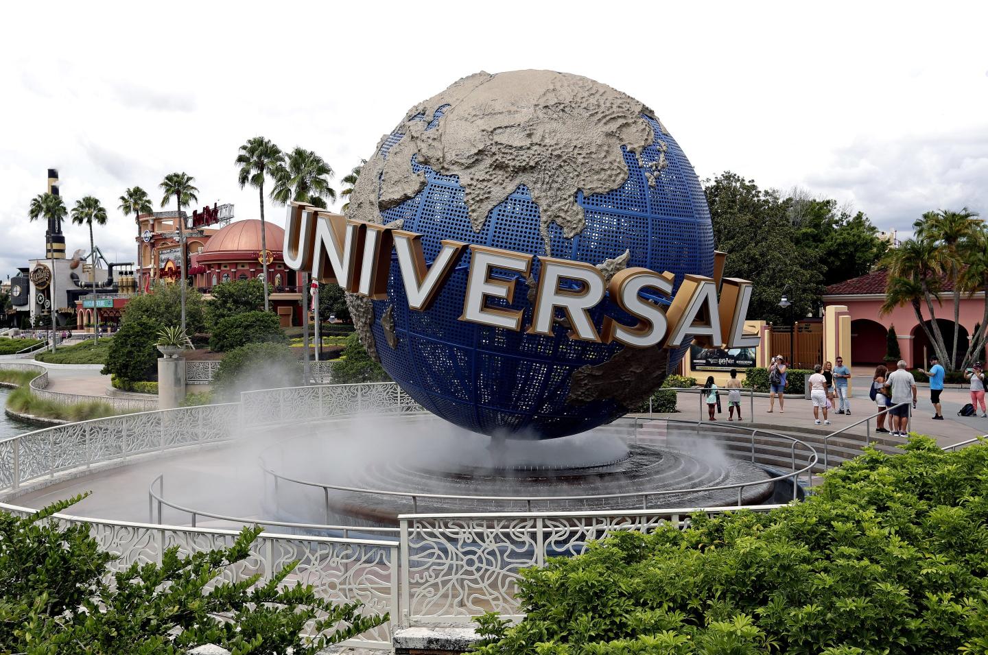 Guests cool off under a water mist by the globe at Universal Studios City Walk at Universal Studios Florida in Orlando, Fla.