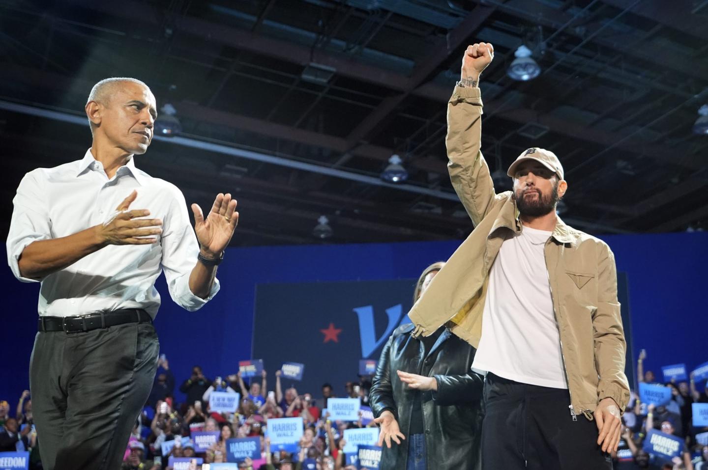 Eminem raises his fist on stage as Barack Obama claps besides him