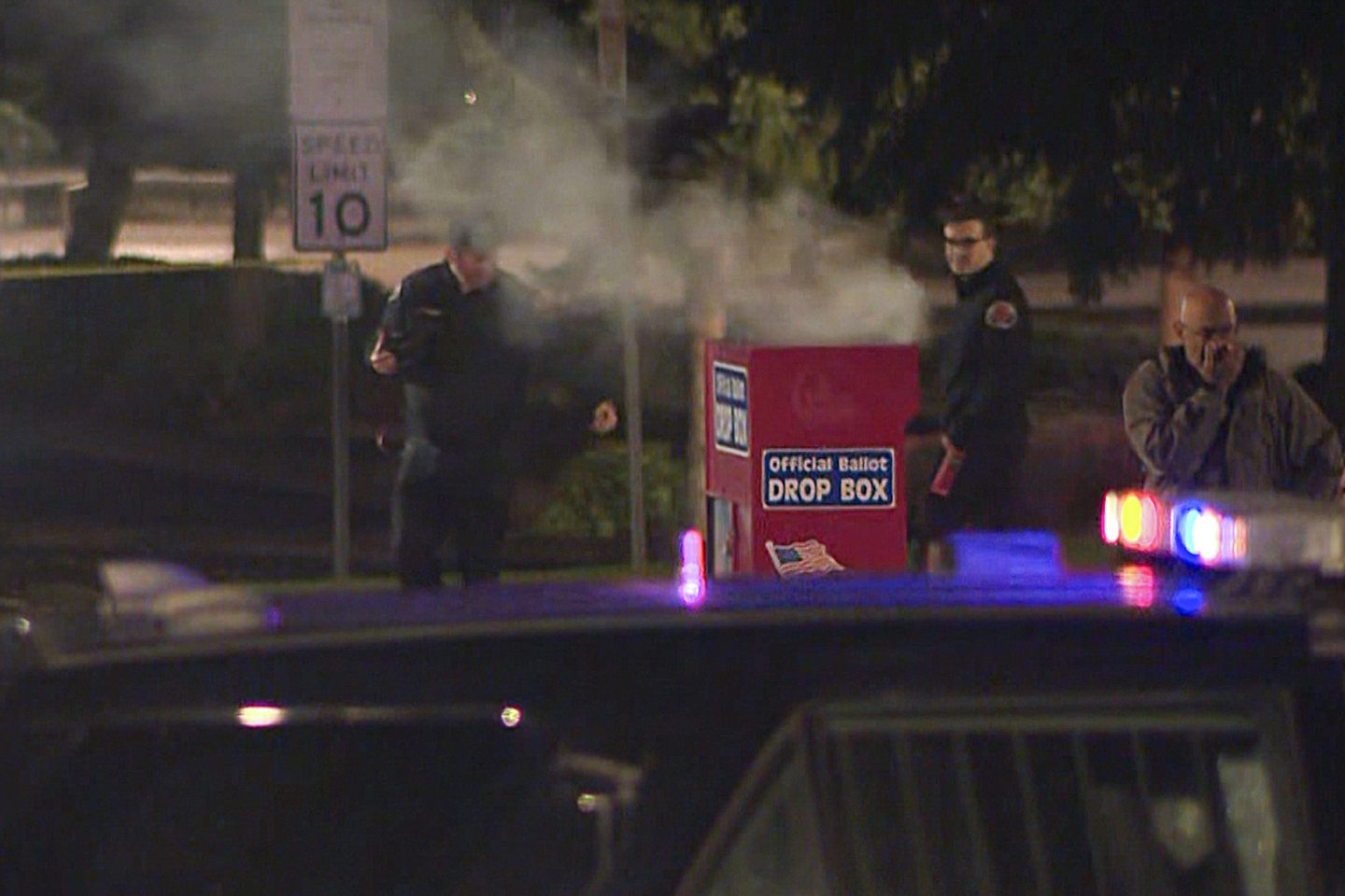 In this image made from a video provided by KGW8, authorities investigate smoke pouring out of a ballot box.