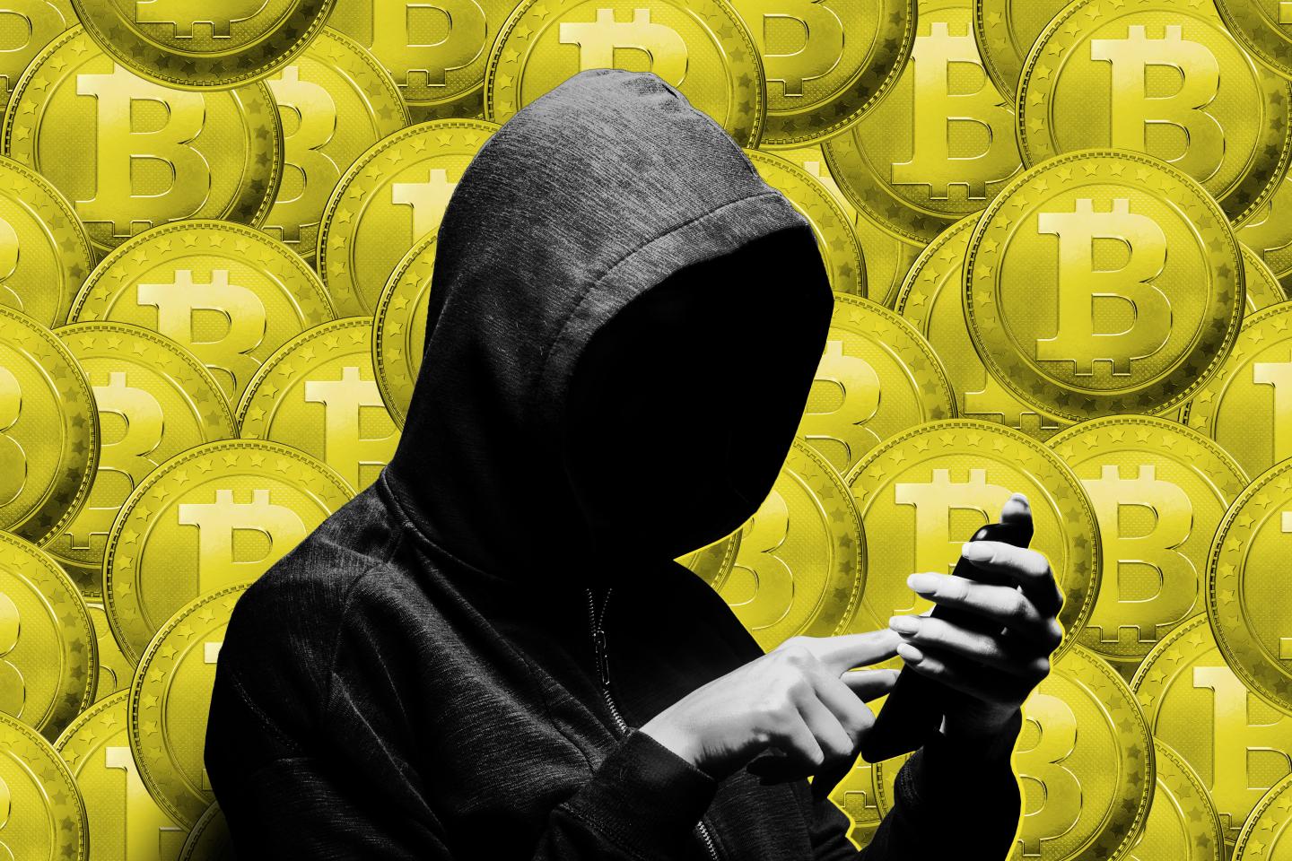 Hooded hacker stealing information with a phone.