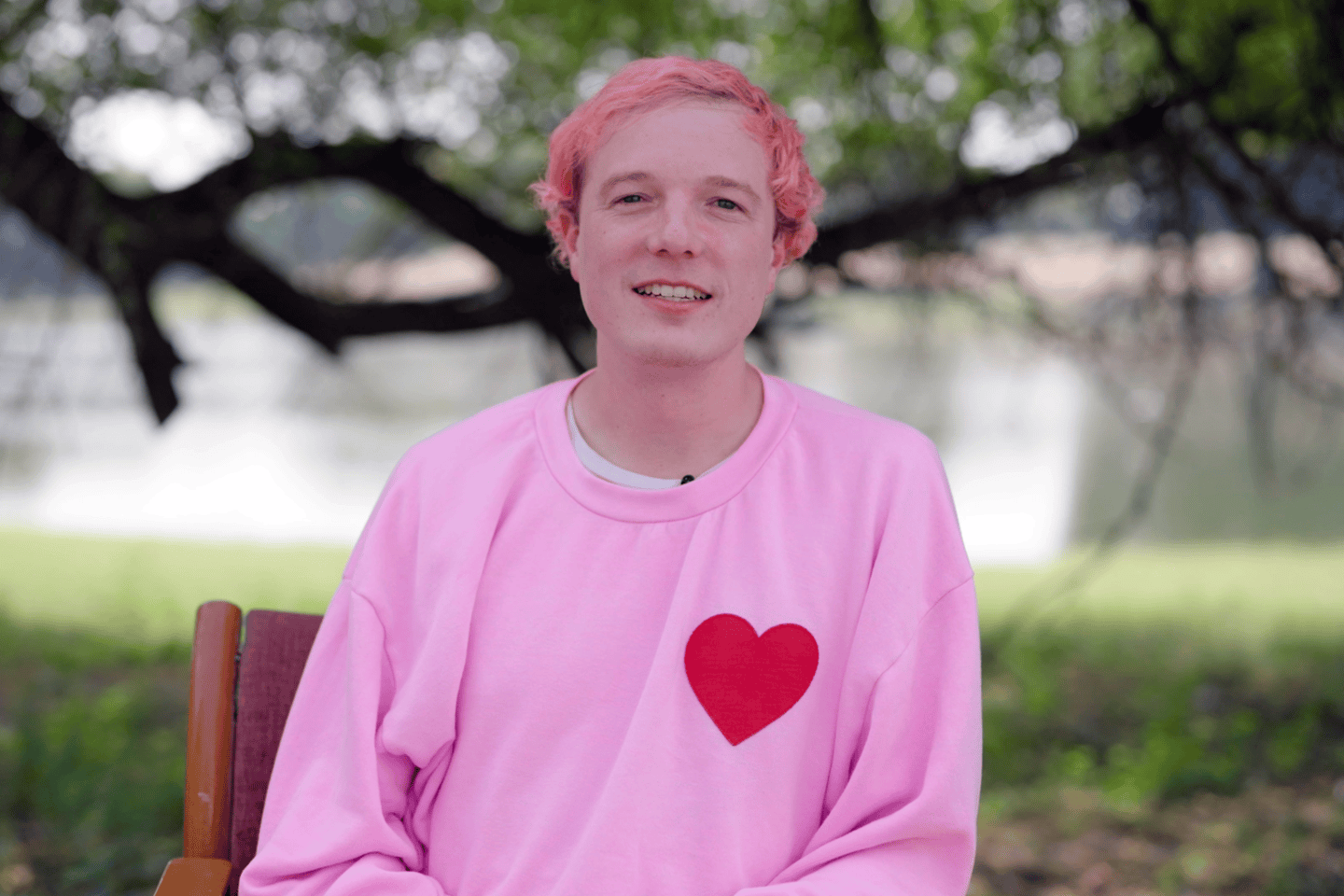 CEO and cofounder David Vorick sits in front of a tree wearing a pink sweatshirt with a red heart on it