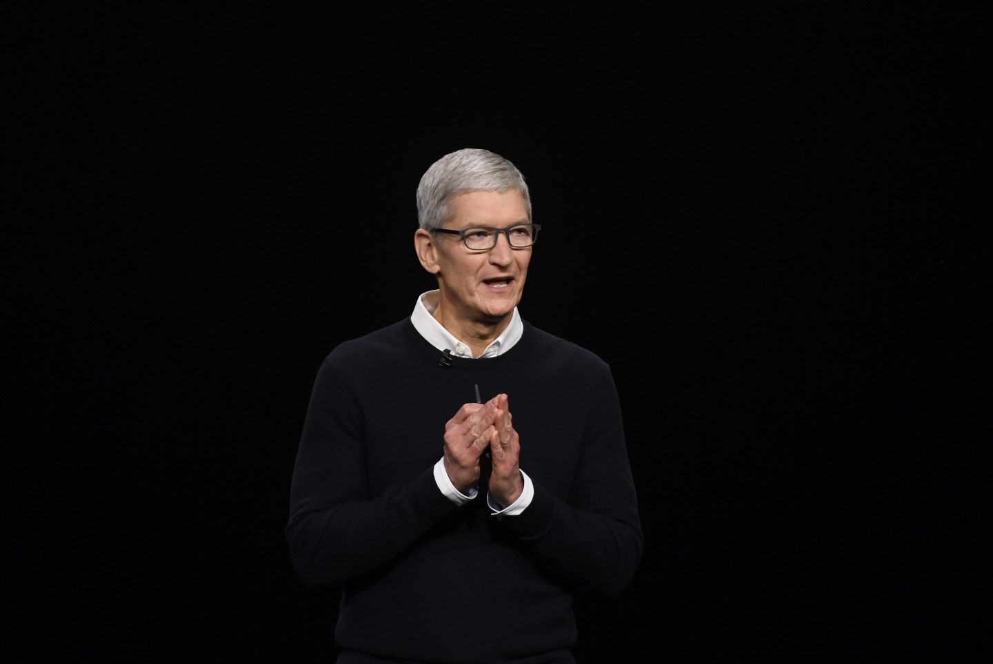 Tim Cook looks away from the camera, holding his hands together and talking.