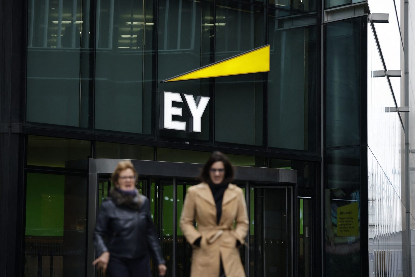 Pedestrians walk past the London EY offices