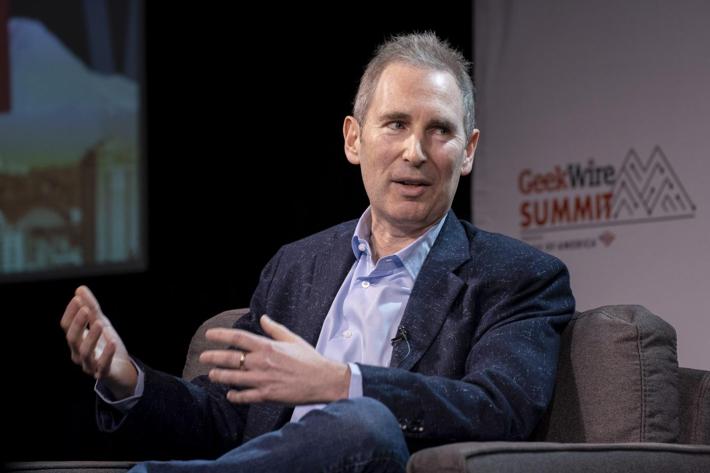 Andy Jassy sits in a chair onstage and gestures as he speaks.