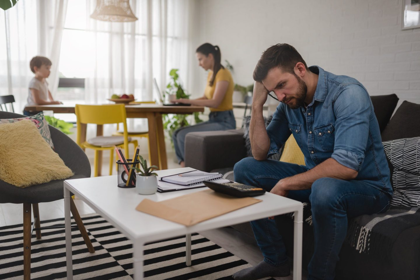 Young man at home with family using a calculator