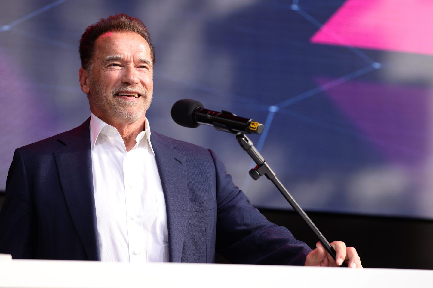 Arnold Schwarzenegger smiling behind a podium.