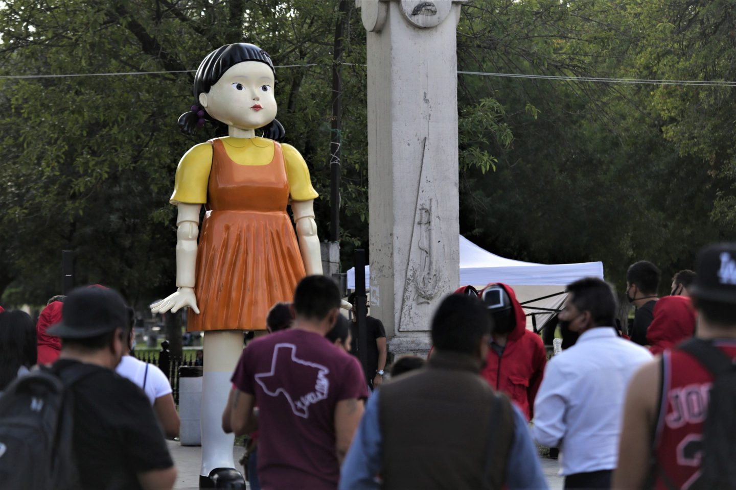 People observe the doll from Netflix's 'El Juego del Calamar' (Squid Game) series at Alameda park on November 3, 2021 in Monterrey, Mexico. This doll is featured in of one of the lethal games in the Netflix fictional series from Korea, 'Squid Game'.