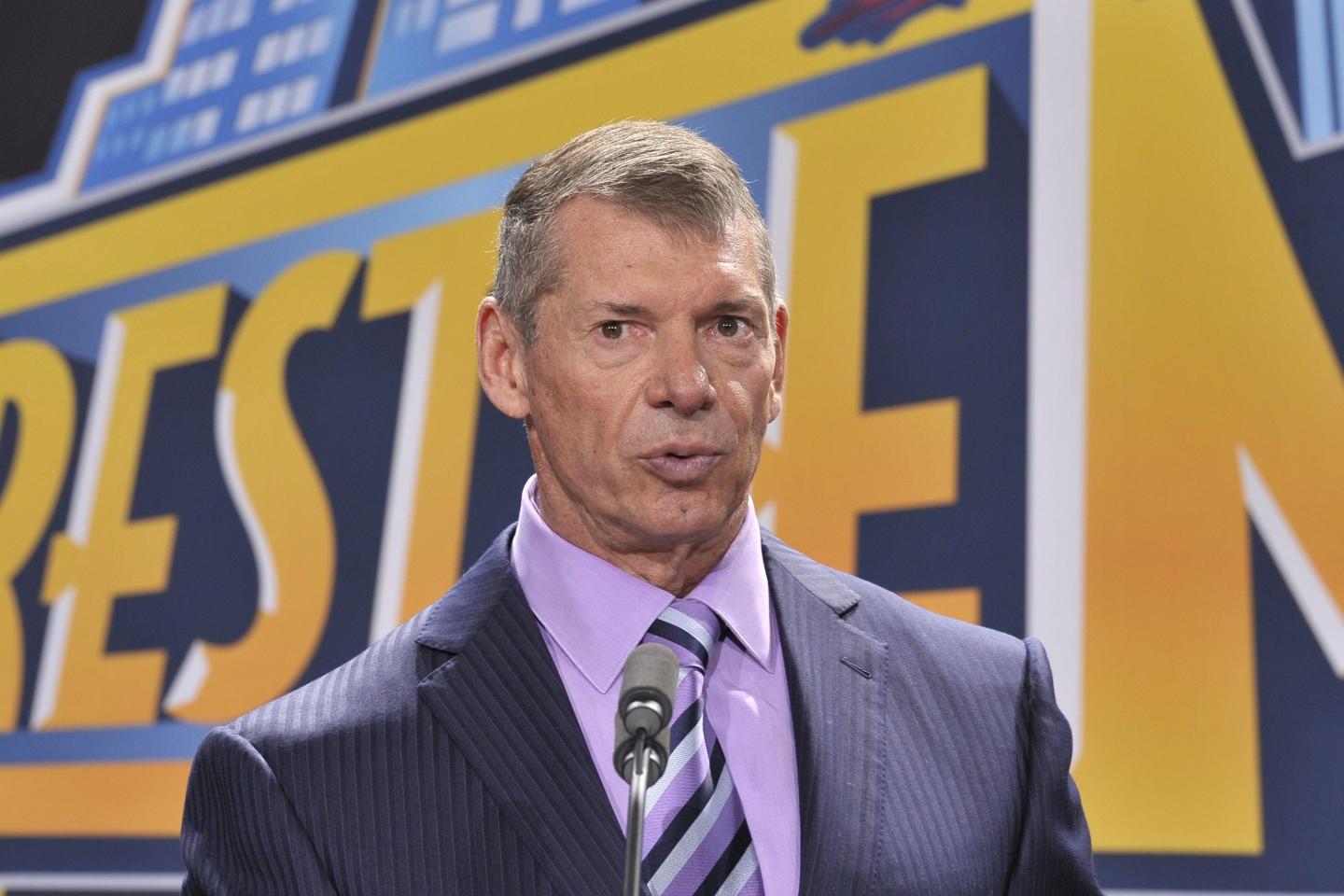 WWE CEO Vince McMahon speaks in front of Wrestlemania artwork